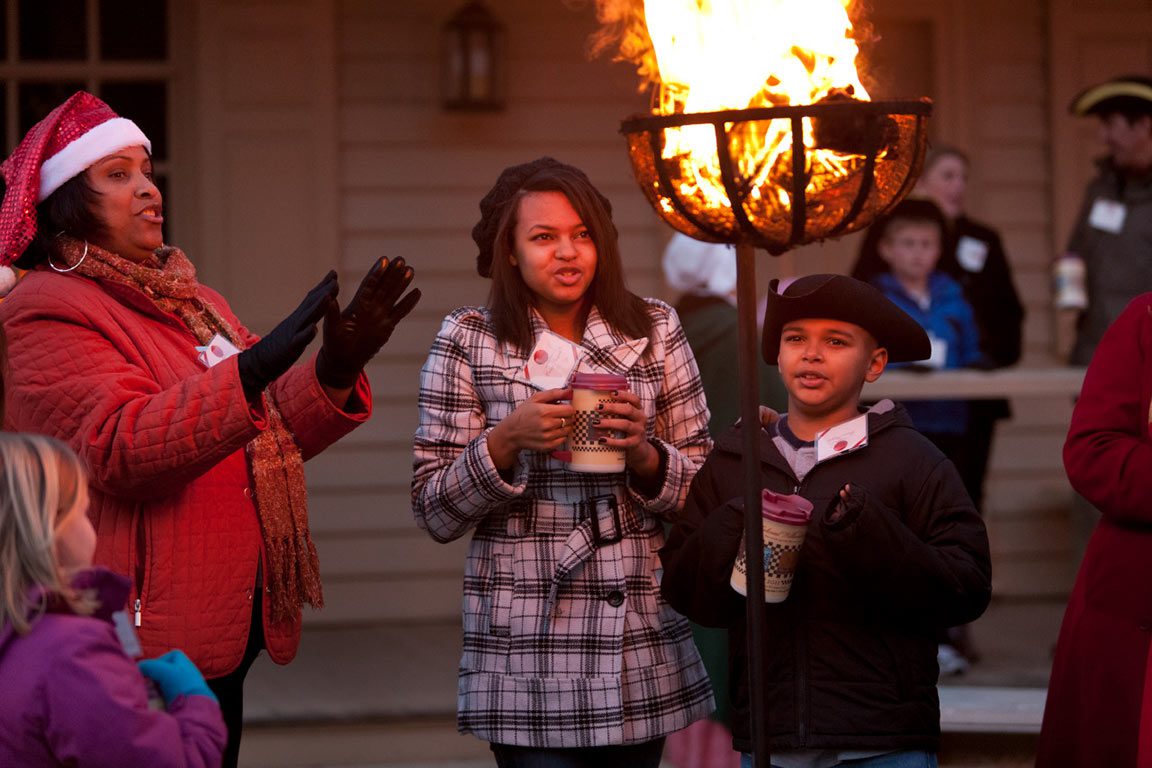 Family warming their hands near an outdoor fire pit while enjoying Christmas Williamsburg VA festive atmosphere.