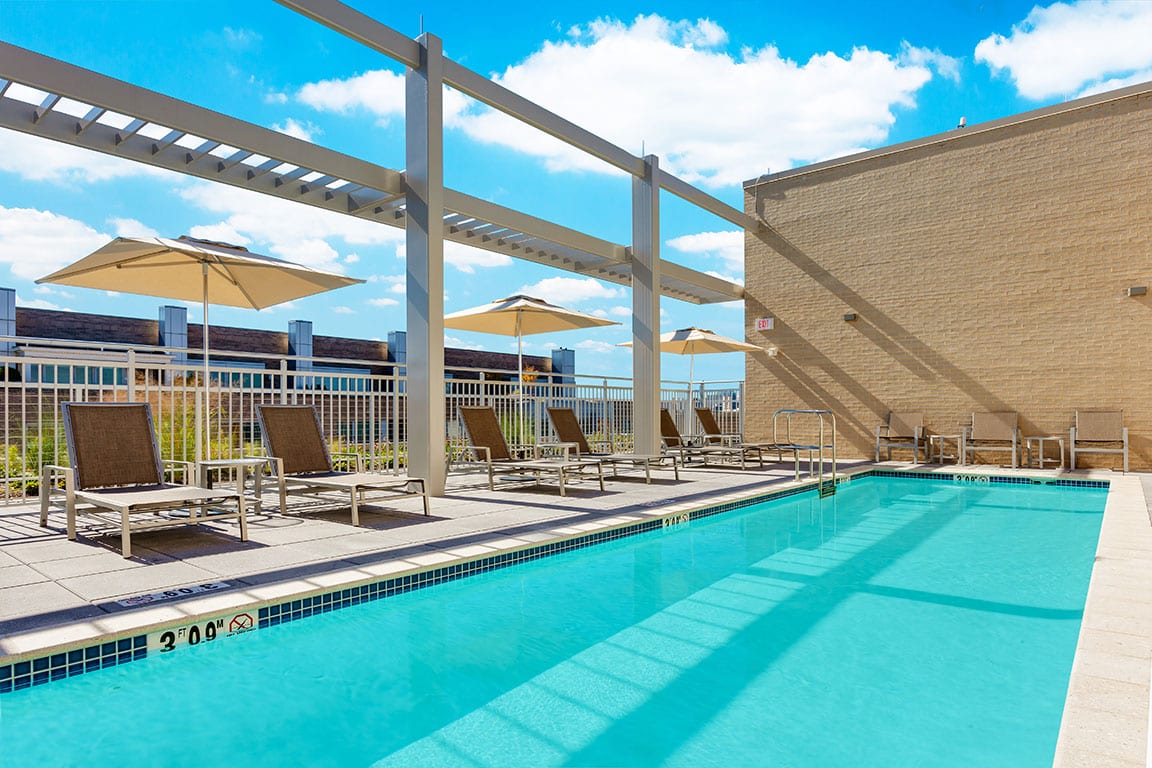 Hilton Garden Inn Washington DC Georgetown Area, a DC hotel with rooftop pool, surrounded by a deck with lounge chairs and greenery.