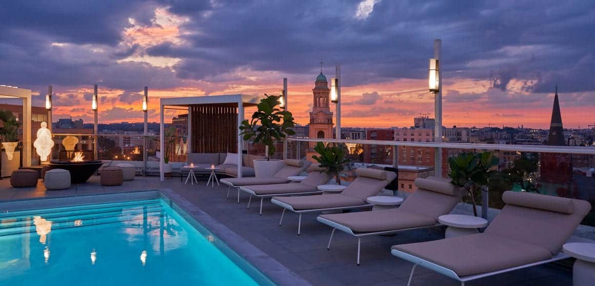DC hotel with rooftop pool at Hotel Zena, featuring lounge chairs and a city skyline view.