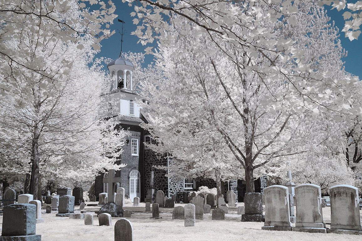 Old Swedes Church covered in a light layer of snow during winter, highlighting its historic charm and festive atmosphere for Christmas in Wilmington DE.
