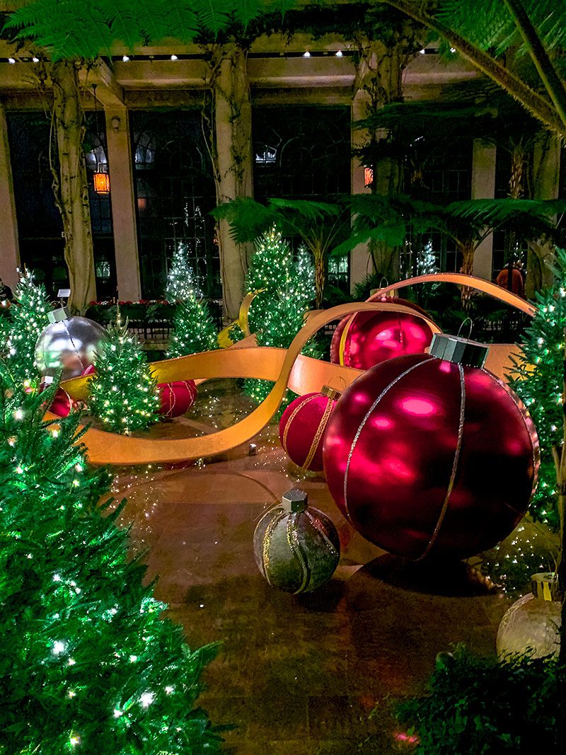 Christmas decorations featuring oversized ornaments and sparkling trees inside a festive display in Wilmington, DE for the holiday season. Christmas in Wilmington DE adds a magical touch with glowing lights and lush greenery.