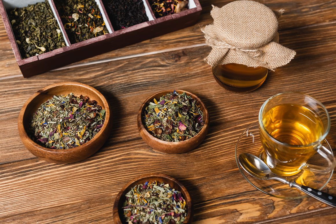 This image shows a variety of loose leaf herbal teas and a glass of brewed tea, similar to the types of teas that might be offered alongside finger foods during afternoon tea Washington DC.